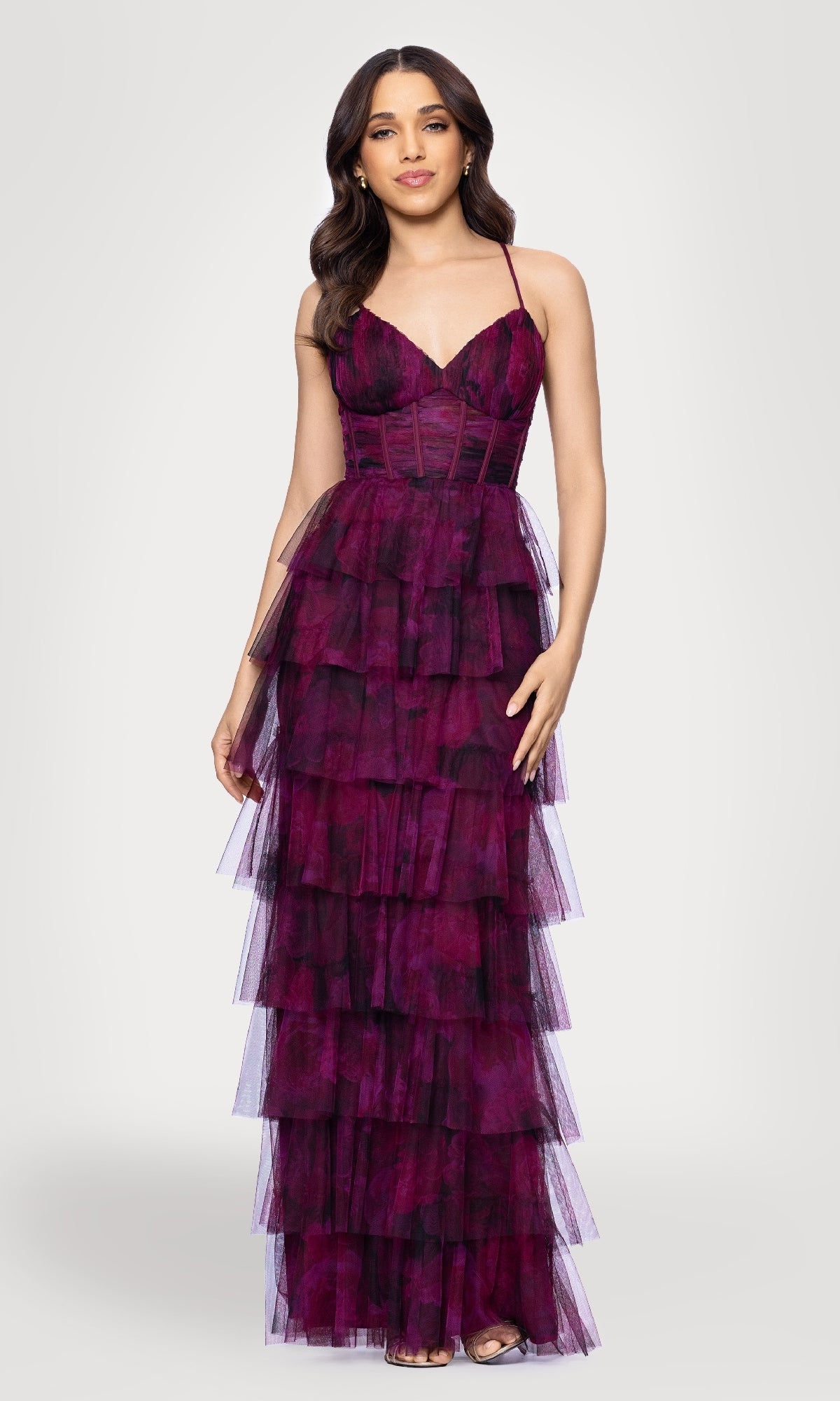 A woman in the Blondie Nites 5778BN Wine Red Ruffle Formal Gown, a sleeveless, floor-length dress with tiered ruffles and spaghetti straps, stands against a plain light background.
